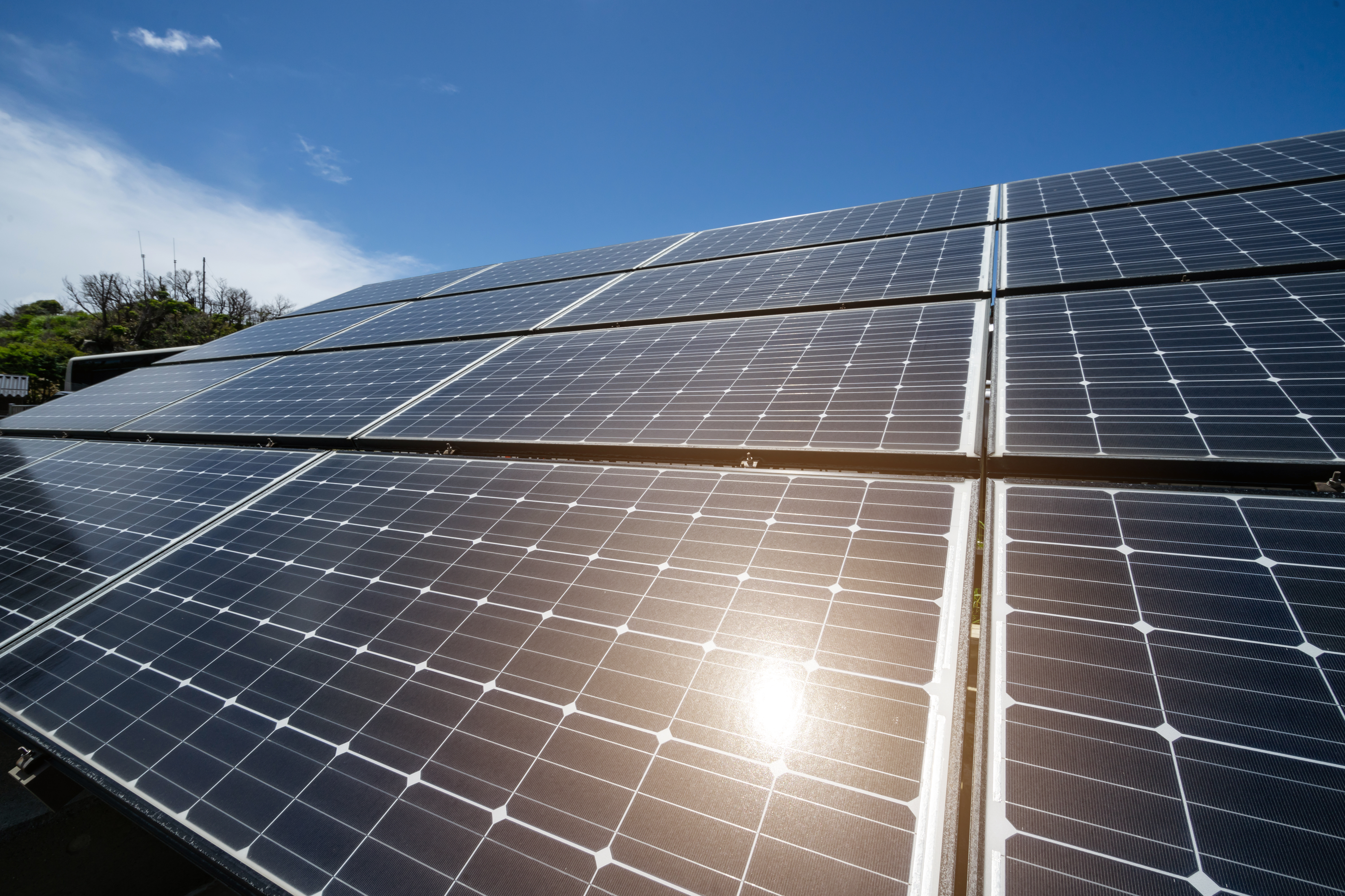 Close-up of rooftop solar panels exporting power under a bright sky